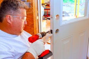 À l'aide d'un tournevis, serrurier professionnel installe poignée de porte de serrure sur une porte d'entrée